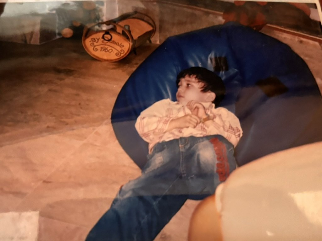 As a kid, arms folded on a blue beanbag